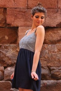 Smiling beautiful woman wearing dress while standing against wall