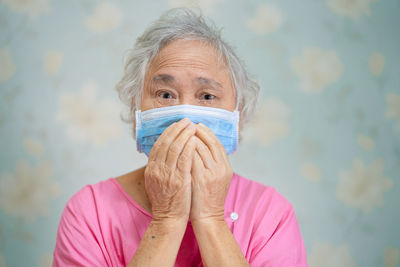 Portrait of senior woman wearing flu mask sitting at hospital