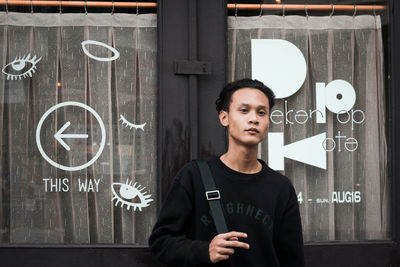 Portrait of young man standing against wall