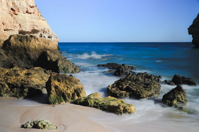 Scenic view of rocks on beach against sky