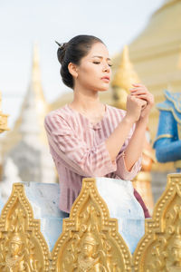 Young woman looking away while standing by railing