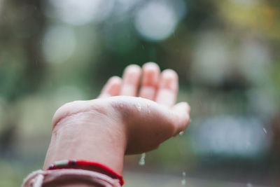 Close-up of hand catching raindrops outdoors