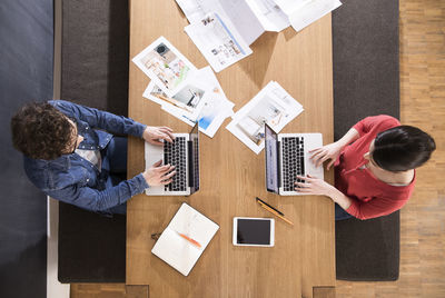 Overhead view of man and woman using laptops on table