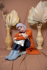 Portrait of woman sitting against wall at home