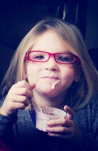 Portrait of cute girl wearing eyeglasses while eating ice cream at home