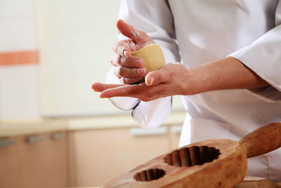 Midsection of woman preparing sweet baking food with dough at kitchen counter