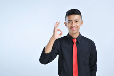 Portrait of young man standing against white background