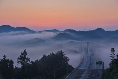 High angle view of road amidst trees against orange sky