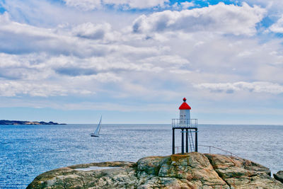 Sailboat and lighthouse on rocky shores 