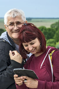 Portrait of smiling man with woman standing on smart phone