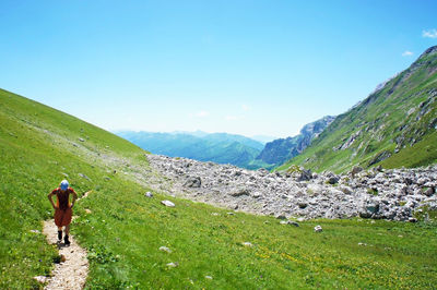 Young caucasian woman hiker walking on mountain trail on background of  green caucasus mountains