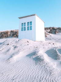 House on snow covered land against clear sky