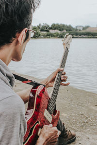 Man playing guitar on riverbank