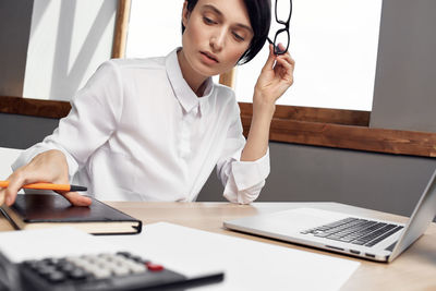 Mid adult woman using mobile phone at table