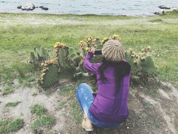 Rear view of woman photographing cactus plants using smart phone