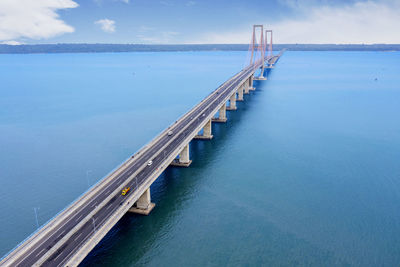 Aerial view of bridge over sea against blue sky