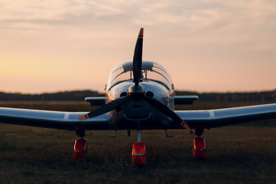 Airplane on airport runway against sky during sunset