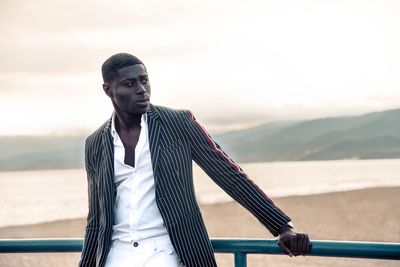 Portrait of young man standing against railing