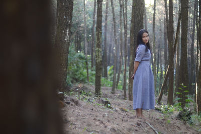 Woman standing by trees in forest