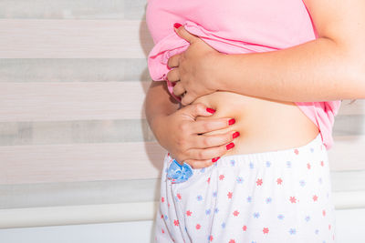 Midsection of woman with arms crossed standing at home