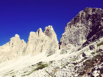 Low angle view of snowcapped mountain against clear blue sky