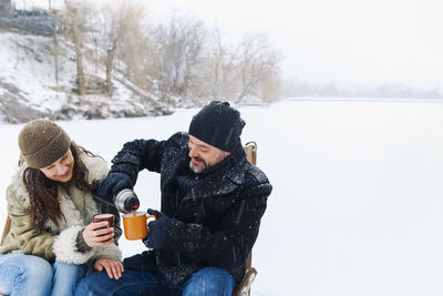 Rear view of woman sitting on snow covered field