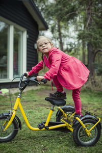 Portrait of girl with down syndrome balancing on bicycle in lawn