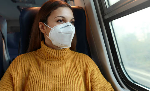 Young woman in mask sitting at bus