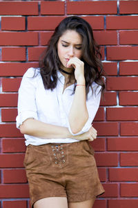 Beautiful young woman standing against red wall