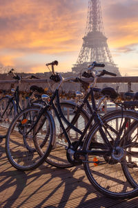 Bicycles parked on bridge in city during sunset