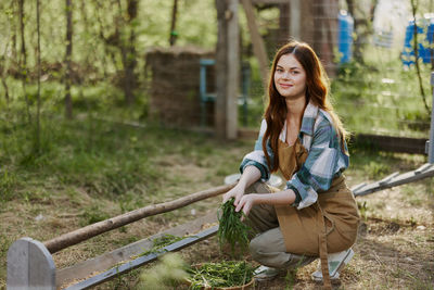 Portrait of young woman standing against trees