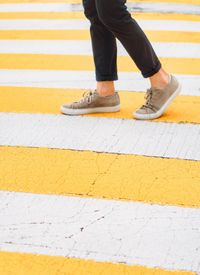 Low section of person walking on zebra crossing 