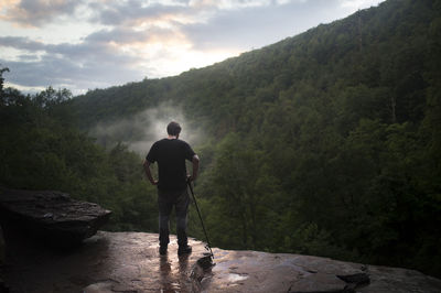 Rear view of man standing on mountain against sky