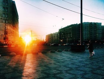 People walking in city against sky during sunset