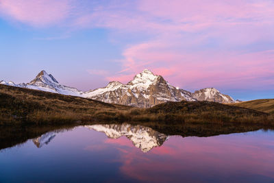 Scenic view of lake by snowcapped mountain against sky during winter