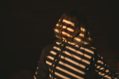 Portrait of woman standing against black background