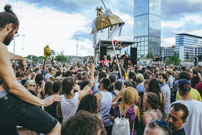 Crowd on street during music festival in city against sky