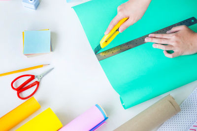 High angle view of woman cutting paper on table