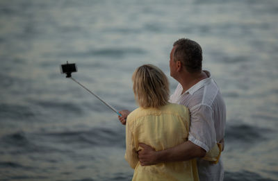 Couple taking selfie while standing at beach