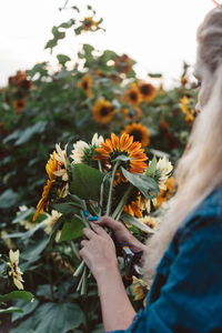 Midsection of woman holding yellow flowering plant