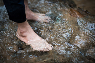 Low section of woman standing in river 