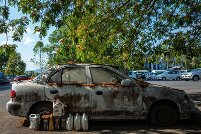 Abandoned car on road against trees