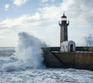 Lighthouse on sea against sky