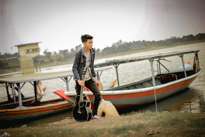 Young man standing on boat against sky