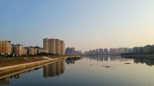 Reflection of city on water against clear sky