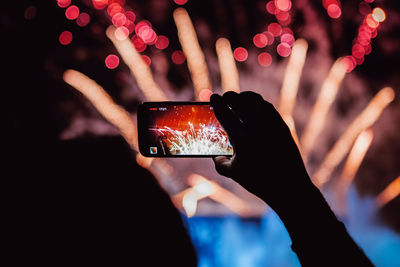 Midsection of person holding mobile phone at night