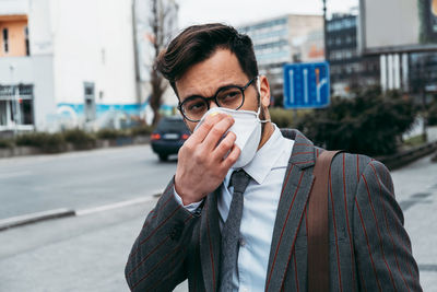 Business man standing on city street with protective face mask.