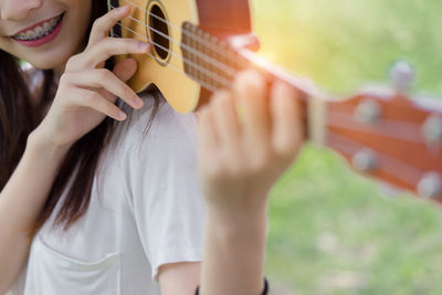 Midsection of woman playing ukulele on grass