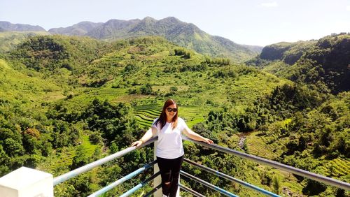 Full length of woman standing on railing against mountain