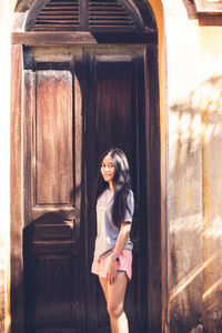 Portrait of woman standing against door